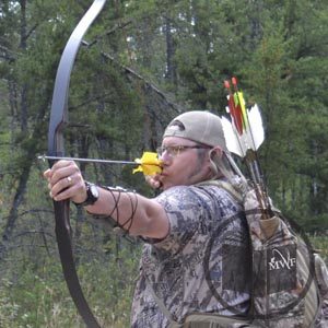 man aiming and drawing a recurve bow