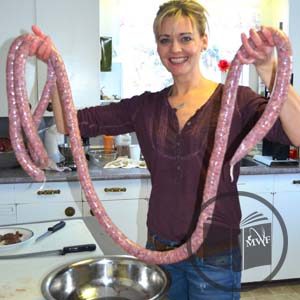 woman smiling and holding up freshly made wild game sausage