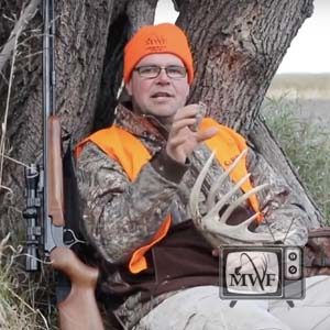 man holding rattling antlers sitting next to a muzzle loader