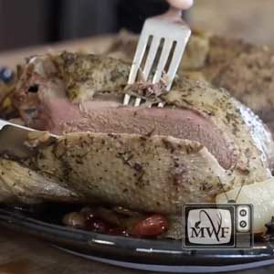 a fork and knife cutting into a slow roasted duck