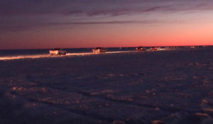 a line of trucks driving onto the ice at the warner road access on lake winnipeg